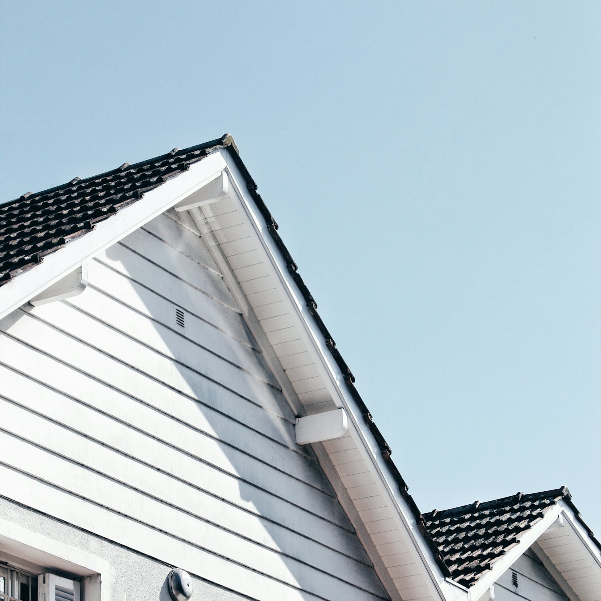 The roof and gables of a white house against a blue sky