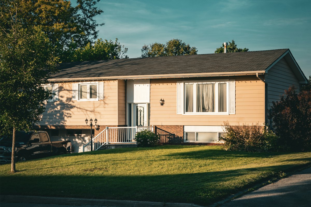 A family home with a shingle roof and a front lawn